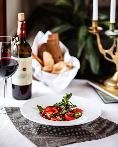 Seitenansicht von frischem Salat mit Tomaten grüner Chili-Pfeffer roter Zwiebel und Granatapfelsauce in einer weißen Schüssel