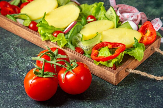 Seitenansicht von frischen Tomaten des gehackten Gemüses mit Stielmesser auf einem Holztablett auf Mischfarbenoberfläche
