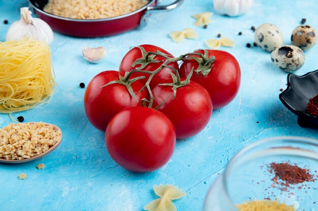 Seitenansicht von frischen Tomaten und rohen Sternen geformten Nudeln auf Blau