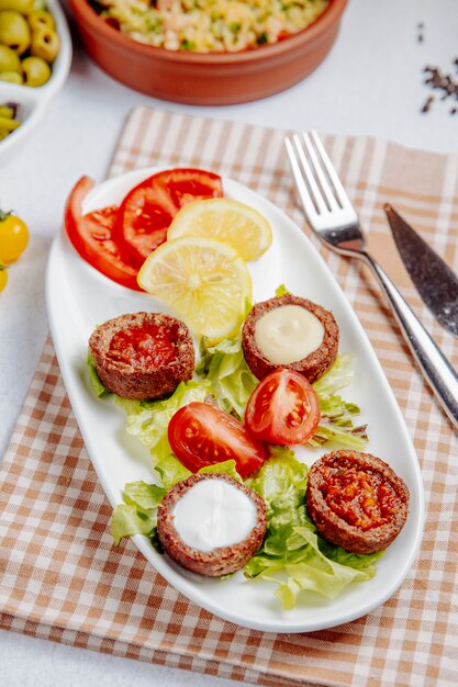 Seitenansicht von gebratenen Kugeln mit Pilzen und Tomaten auf Tisch