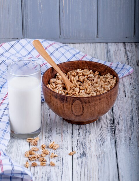 Seitenansicht von gepufftem süßem Reis in Karamell in einer Holzschale, die mit einem Glas Milch auf rustikal serviert wird