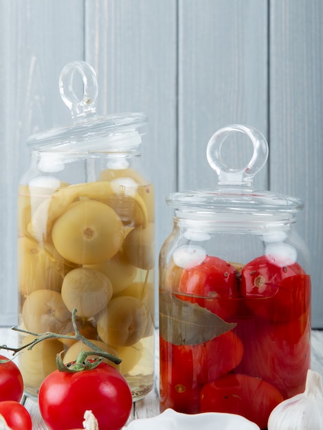 Seitenansicht von Gläsern voller gesalzener Tomaten auf hölzernem Hintergrund mit Kopienraum