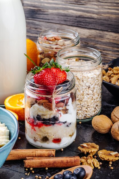 Seitenansicht von Hafer über Nacht mit frischen Blaubeeren und Erdbeeren und Joghurt in einem Glas auf dem Tisch