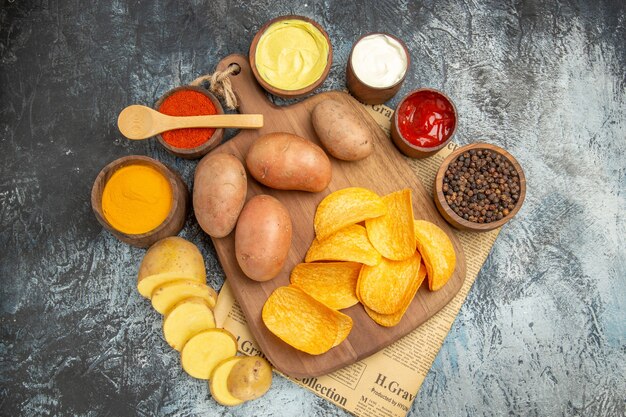 Seitenansicht von hausgemachten köstlichen Kartoffelchips und verschiedenen Gewürzen Mayonnaise-Kethup-Soße auf Zeitung