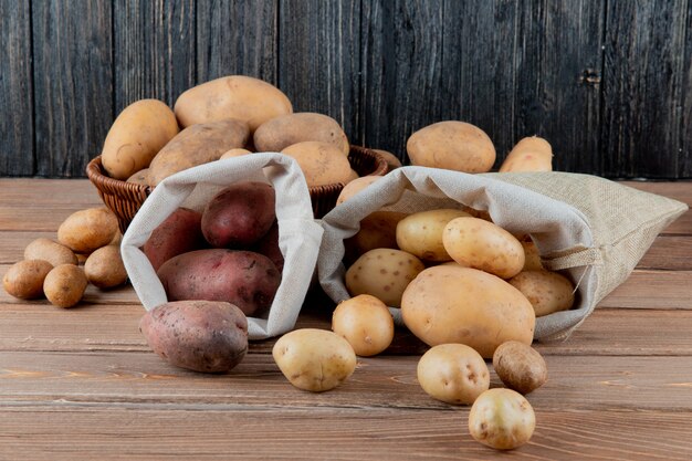 Seitenansicht von Kartoffeln, die aus Säcken auf Holzoberfläche und Hintergrund mit Kopienraum verschüttet werden