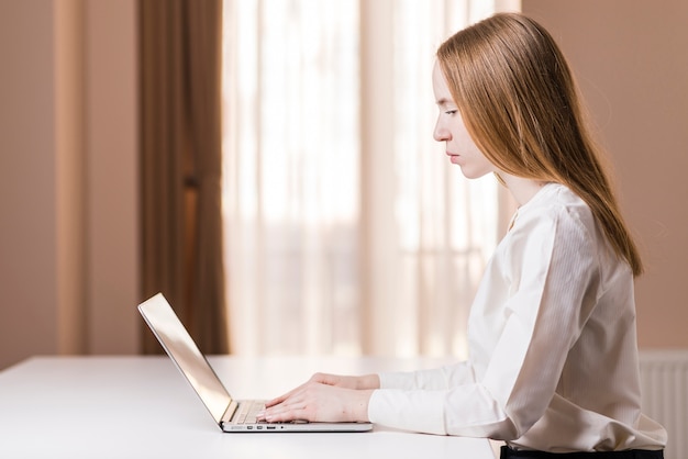 Kostenloses Foto seitenansicht von konzentriertem mädchen mit ihrem laptop