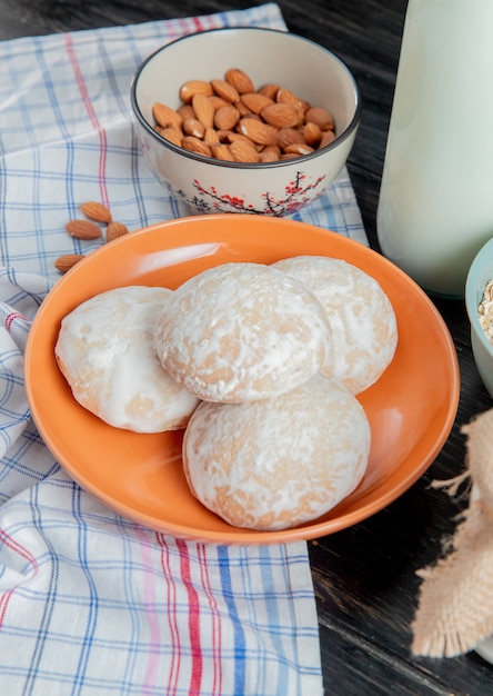 Seitenansicht von Lebkuchen in Platte mit Mandeln auf kariertem Stoff und saurer geronnener Milch auf Holzoberfläche