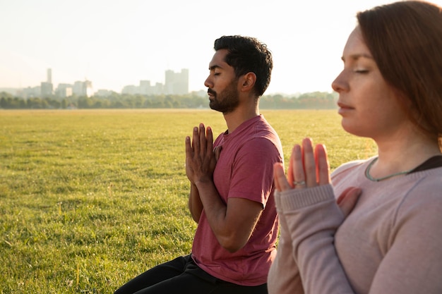 Seitenansicht von Mann und Frau, die im Freien mit Kopienraum meditieren