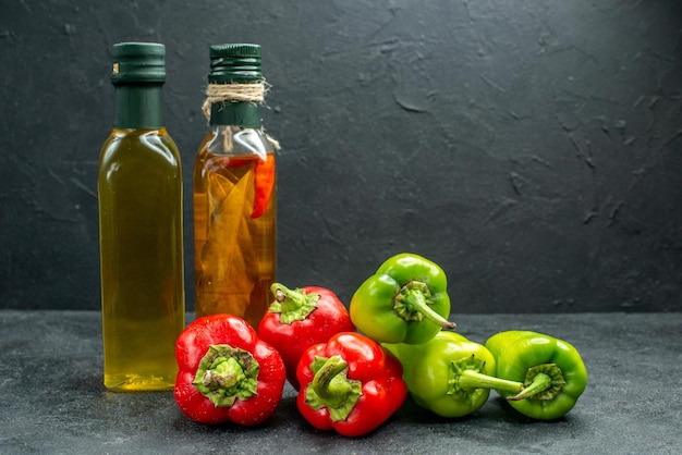 Kostenloses Foto seitenansicht von paprika- und öl- und essigflaschen auf dunkelgrünem tisch mit dunkelgrauem hintergrund