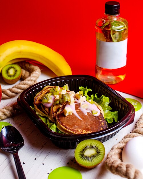 Seitenansicht von Pfannkuchen mit Joghurt und Kiwi in Lieferbox