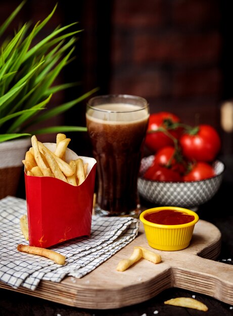 Seitenansicht von Pommes Frites in Pappbeutel mit Ketchup auf Holzschneidebrett