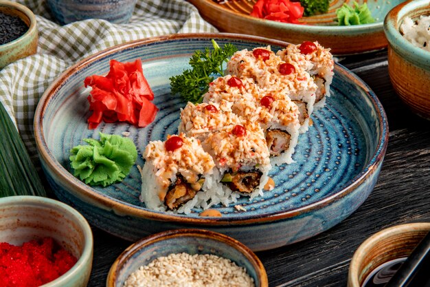 Seitenansicht von Sushi-Rollen mit Reisgarnelen-Tempura-Avocado und Käse innen auf einem Teller mit Ingwer und Wasabi