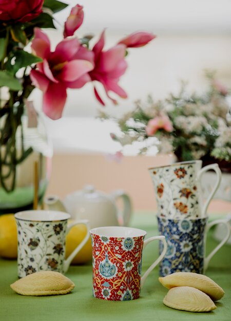 Seitenansicht von Teetassen mit orientalischem Muster und traditioneller aserbaidschanischer Süße Shekerbura auf Blumenwand