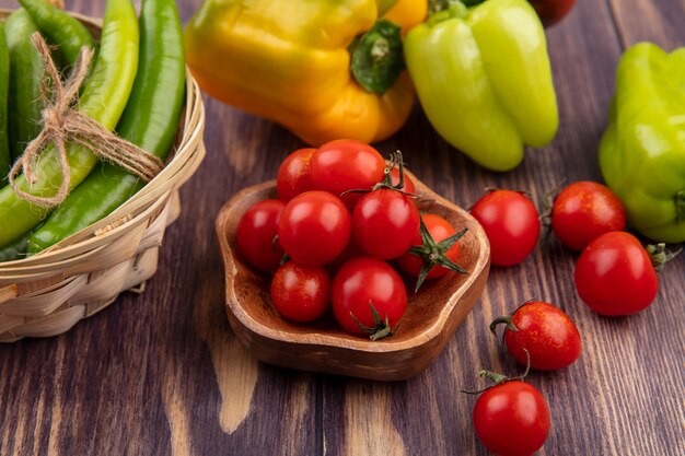 Seitenansicht von Tomaten in Schüssel und Paprika im Korb und auf Holz