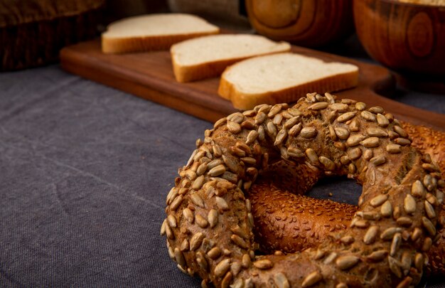 Seitenansicht von türkischen Bagels mit geschnittenem Weißbrot auf kastanienbraunem Hintergrund mit Kopienraum