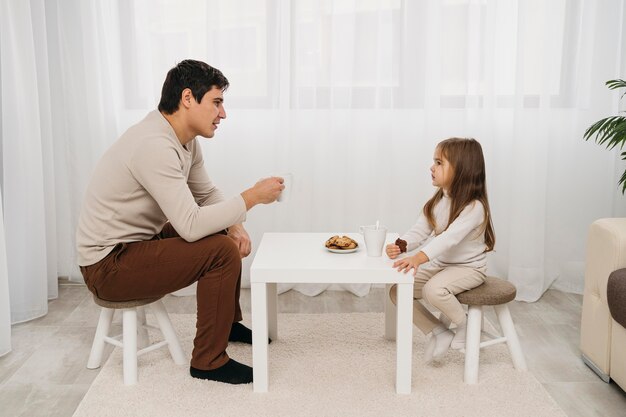 Seitenansicht von Vater und Tochter, die zusammen zu Hause essen