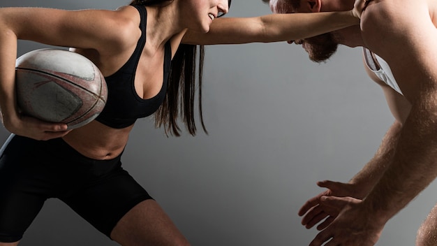 Seitenansicht von weiblichen und männlichen Rugbyspielern, die über Ball kämpfen