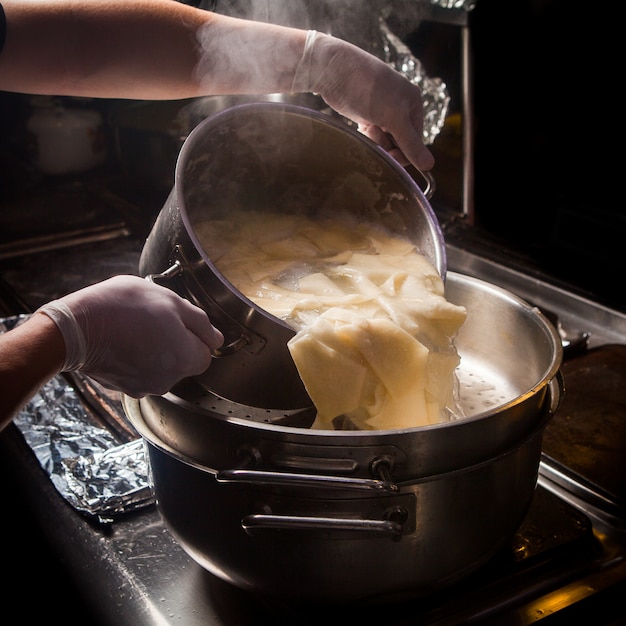 Kostenloses Foto seitenansicht xengel mit tiefem topf und kochendem wasser und menschlicher hand im ofen