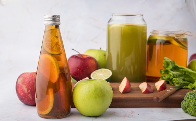 Kostenloses Foto seitenansicht zitronentee mit zimtscheibe limette frischen apfelsaft brocoli salatblatt rote und grüne äpfel