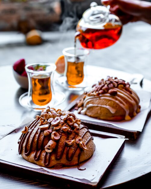 Seitenansicht zwei Brötchen mit Nüssen und zwei Armouda-Gläsern Tee auf dem Tisch