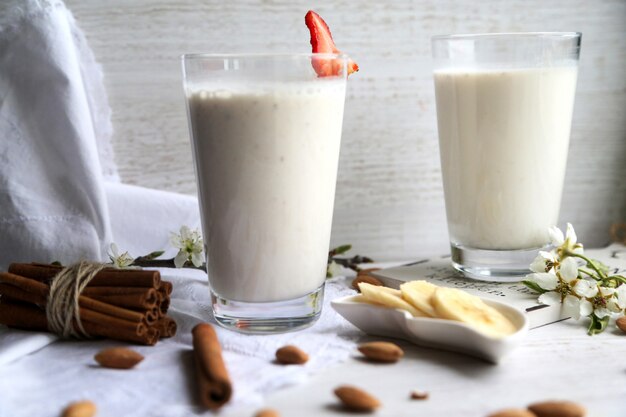 Seitenansicht zwei Gläser Milch mit in Zimt geschnittenen Bananen und Erdbeeren