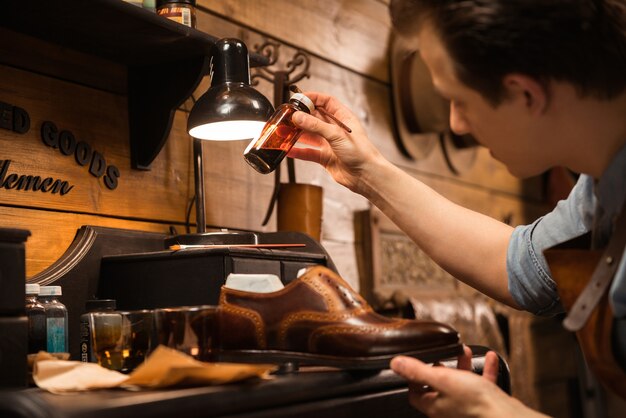 Seitenansichtbild des jungen konzentrierten Schuhmachers