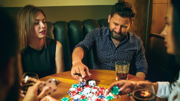 Seitenansichtfoto von Freunden, die am Holztisch sitzen. Freunde, die Spaß beim Brettspiel haben.