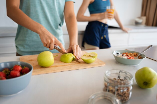 Seitenansichtfrau, die Apfel schneidet