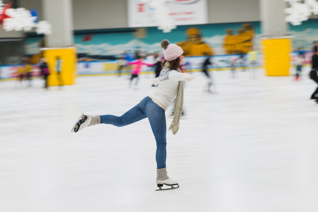 Seitenansichtfrau, die auf Eisbahn eisläuft