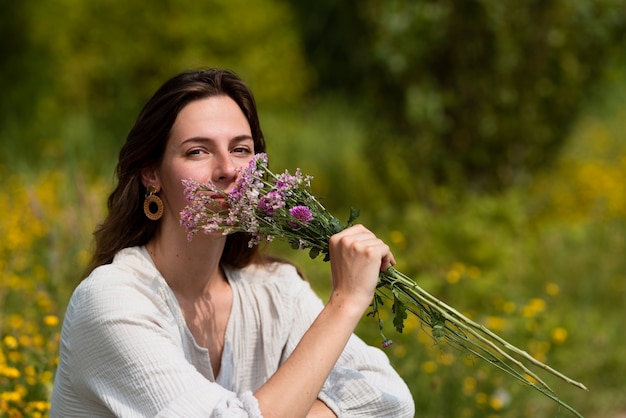 Kostenloses Foto seitenansichtfrau, die blumen riecht