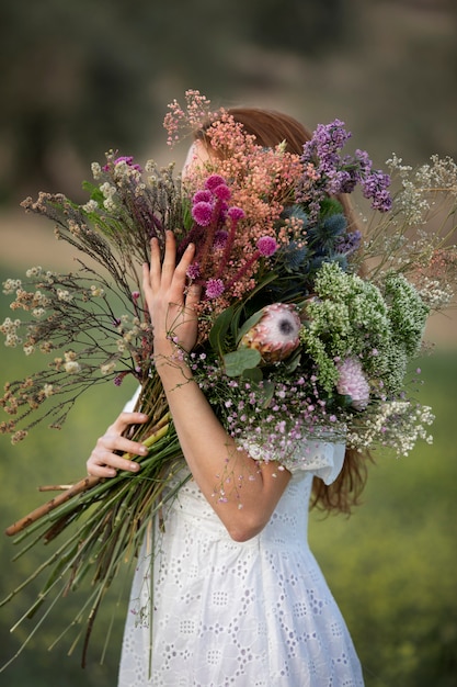 Seitenansichtfrau, die Blumenblumenstrauß hält