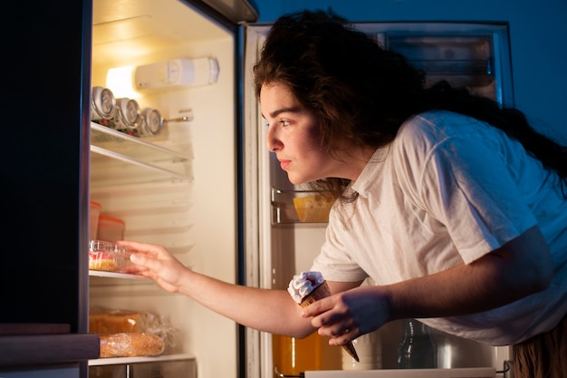 Seitenansichtfrau, die den Kühlschrank überprüft