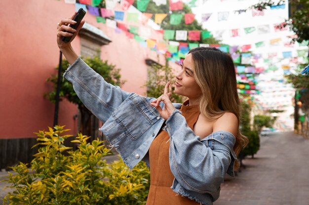 Seitenansichtfrau, die draußen selfie macht