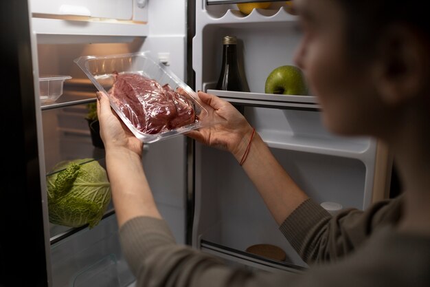 Seitenansichtfrau, die Fleisch hält