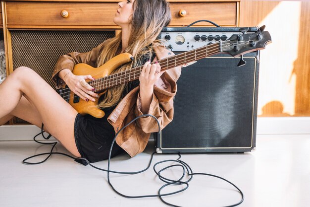 Seitenansichtfrau, die Gitarre auf Boden spielt