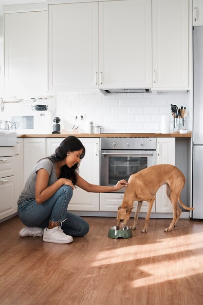 Seitenansichtfrau, die Hund füttert