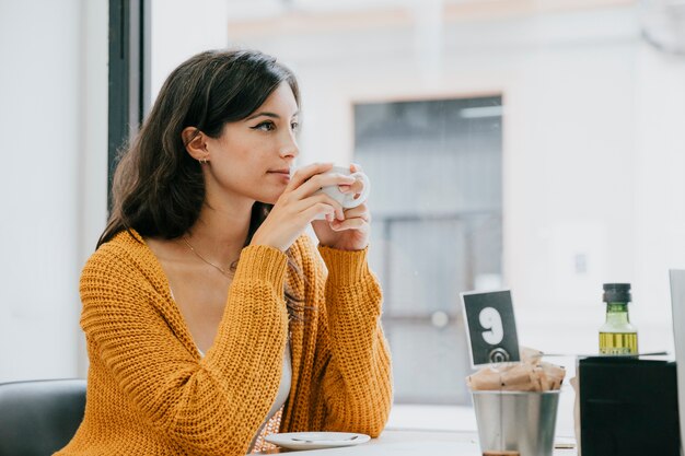 Seitenansichtfrau, die im Café trinkt