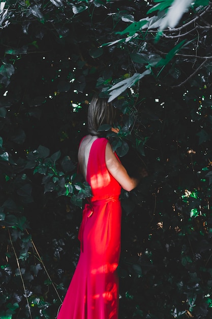 Kostenloses Foto seitenansichtfrau, die in den büschen steht