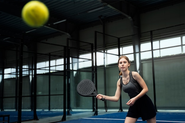 Seitenansichtfrau, die Paddle-Tennis spielt