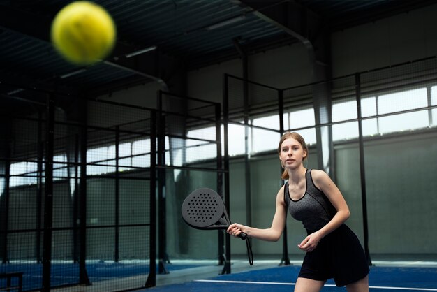 Seitenansichtfrau, die Paddle-Tennis spielt