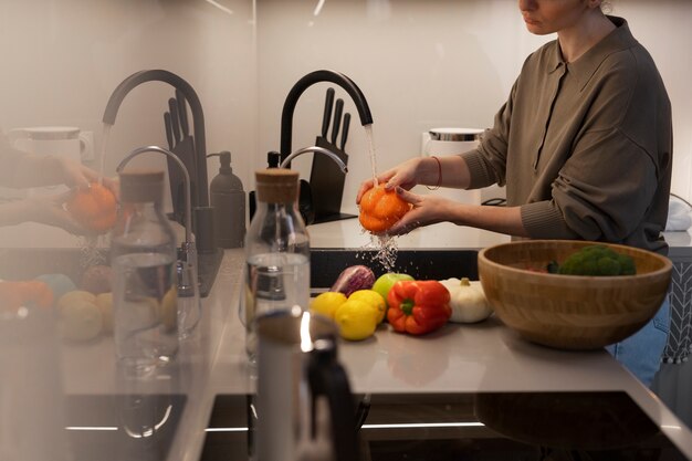 Seitenansichtfrau, die Paprika wäscht