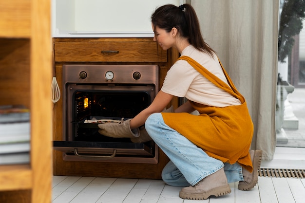 Kostenloses Foto seitenansichtfrau, die pizza kocht