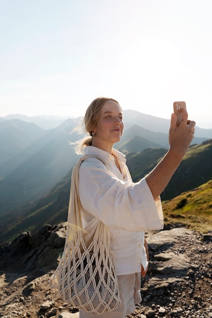 Kostenloses Foto seitenansichtfrau, die selfie auf berg nimmt