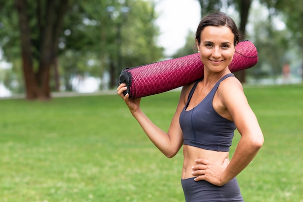 Seitenansichtfrau, die Yogamatte hält