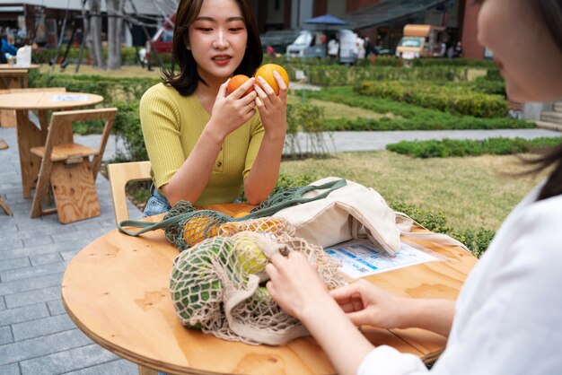 Seitenansichtfrauen, die mit Früchten am Tisch sitzen