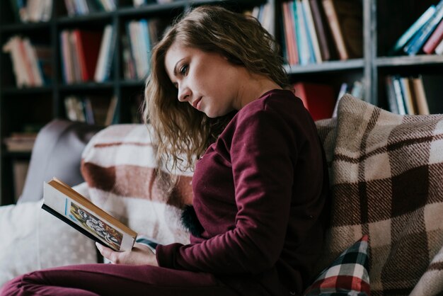 Seitenansichtfrauen-Lesebuch auf Sofa