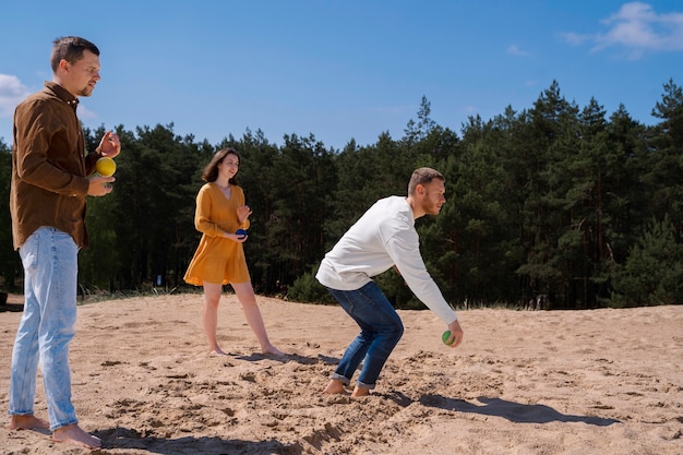 Seitenansichtfreunde, die am Strand spielen