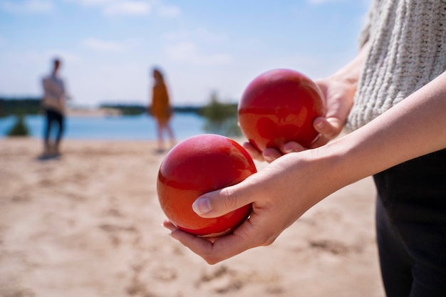 Seitenansichthände, die rote Bälle am Strand halten