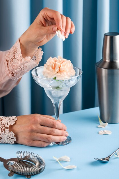 Seitenansichthand, die Cocktail mit Blume zubereitet