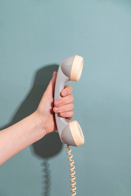 Seitenansichthand, die Telefon mit blauem Hintergrund hält